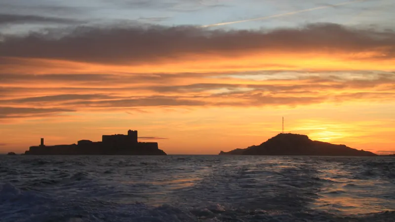 Coucher de soleil orangé derrière le château d'If et les îles du Frioul, vu depuis Marseille