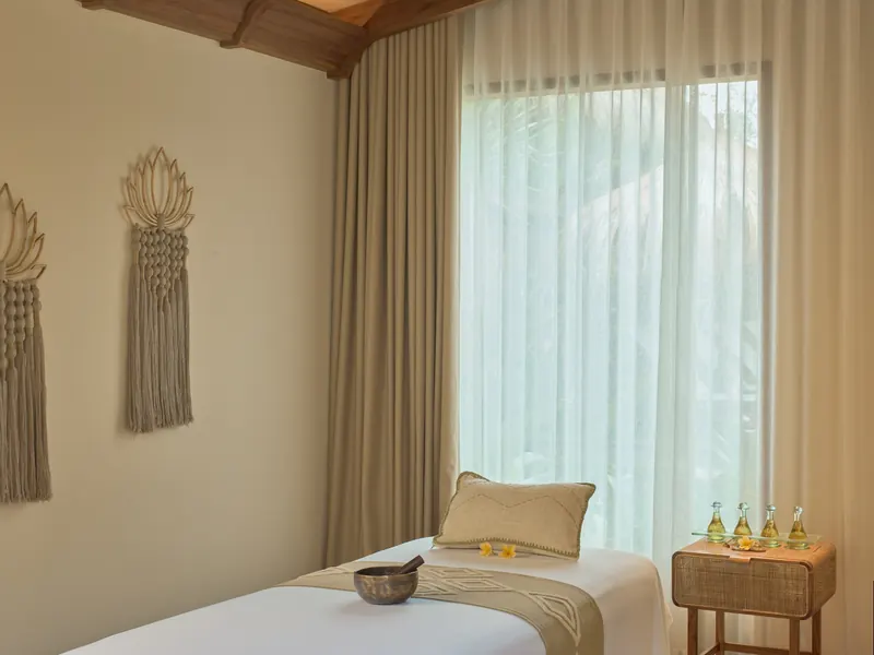 Cabine de soin d'un spa avec table de massage, lumière douce et rideaux clairs