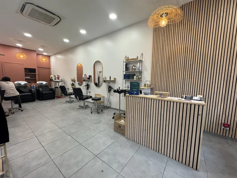 Intérieur d'un salon de coiffure moderne avec comptoir d'accueil en bois et postes de coiffage