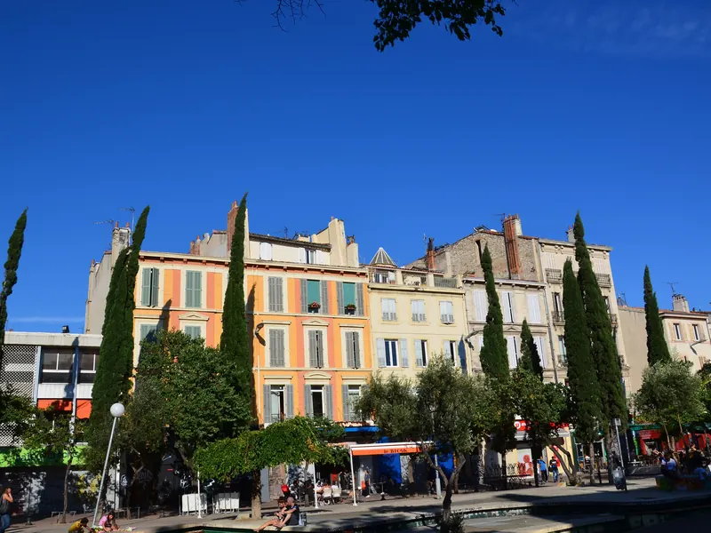 Façades colorées et commerces du cours Julien, bordé de cyprès, à Marseille
