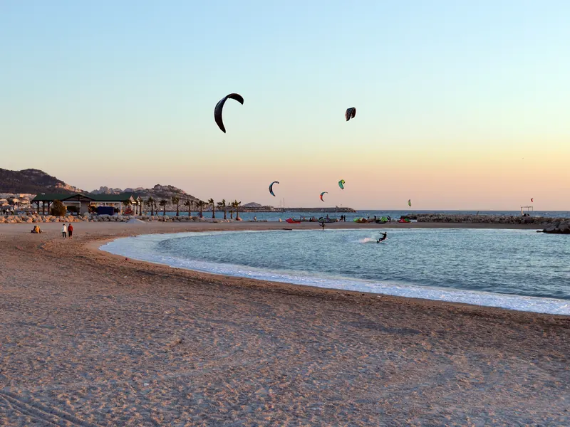 Plage de Bonneveine à Marseille au crépuscule, avec des kitesurfs dans le ciel