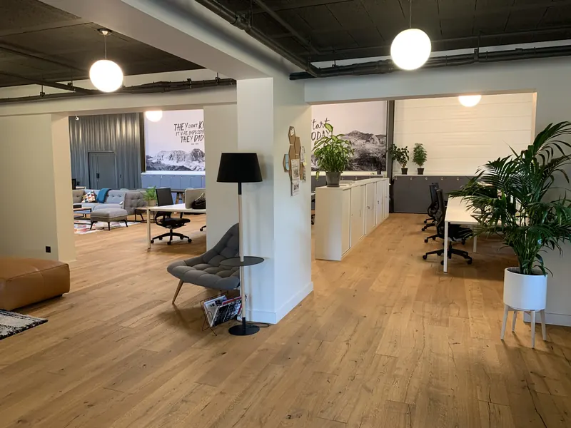 Espace de bureaux et de coworking lumineux avec parquet, plantes et postes de travail