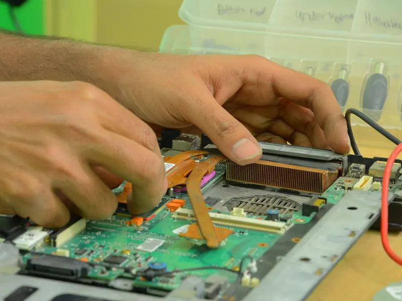 Mains d'un technicien réparant la carte mère d'un ordinateur portable